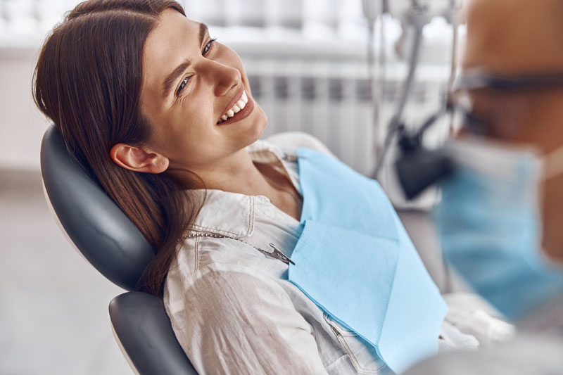 Professional doctor is checking woman's teeth in light modern dental clinic